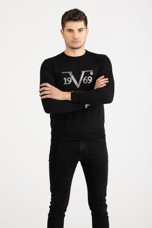 Front view of a man wearing a black Versace 19.69 Abbigliamento Sportivo sweatshirt with silver 19V69 Milano Italia linear logo.