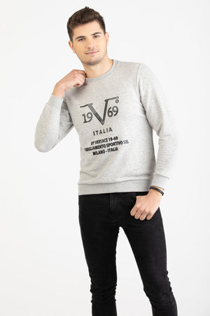 Man wearing a heather grey Versace 19.69 sweatshirt with black linear 19V69 Italia branding.