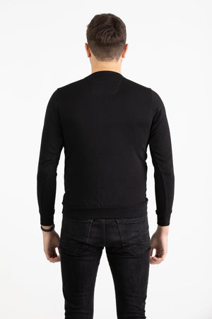 Man wearing a black Versace 19.69 sweatshirt featuring a large grey nylon utility pocket with zipper and snap details.