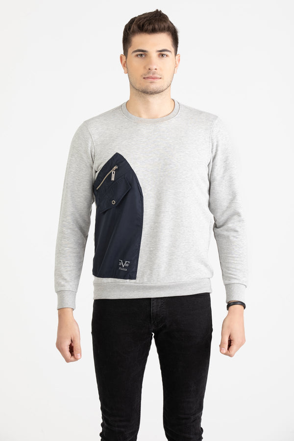 Man wearing a heather grey Versace 19.69 sweatshirt featuring a large navy nylon utility pocket with zipper and snap details.