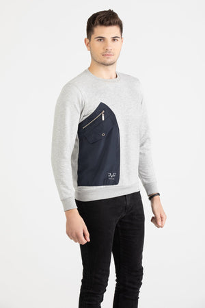 Man wearing a heather grey Versace 19.69 sweatshirt featuring a large navy nylon utility pocket with zipper and snap details.