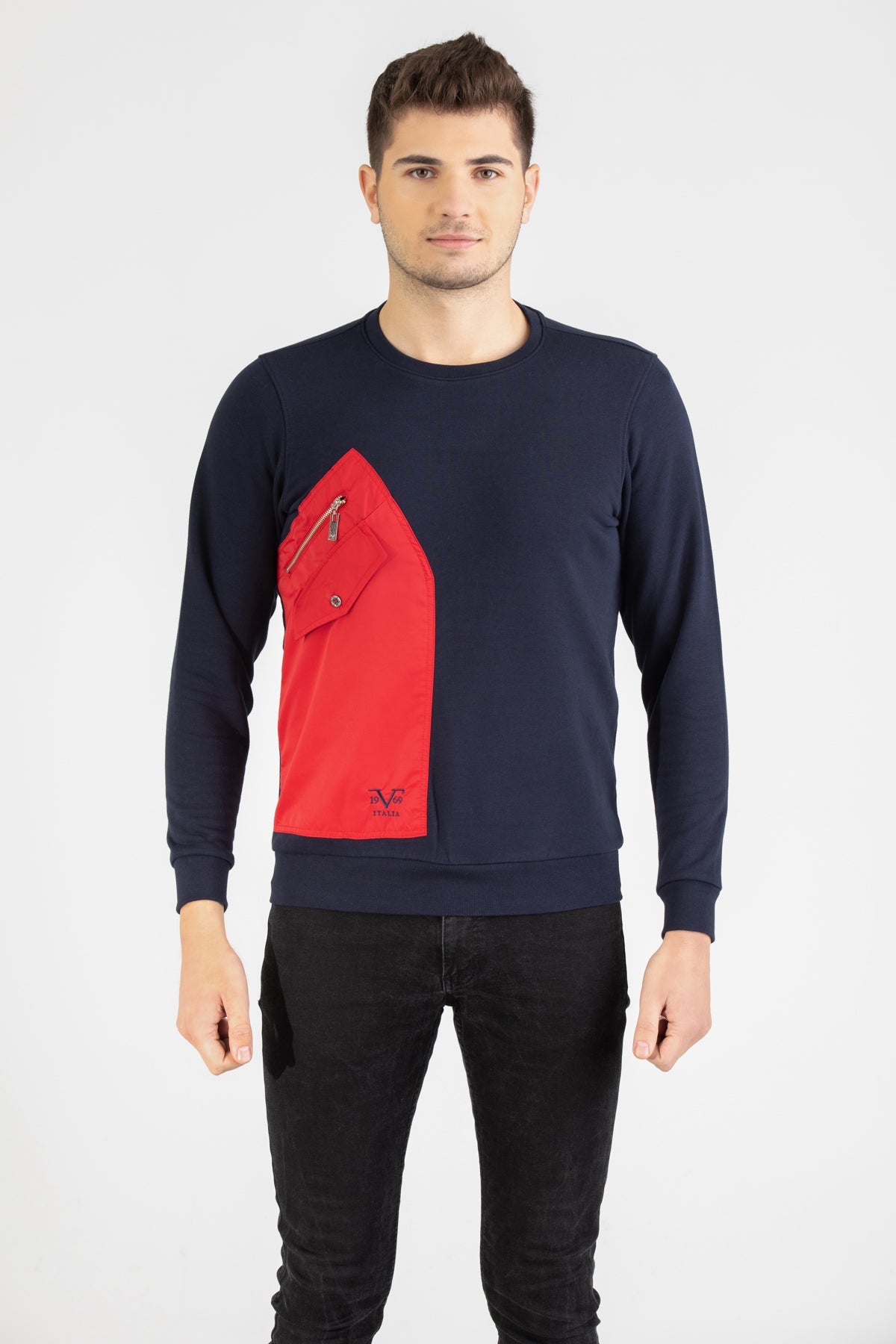 Man wearing a navy blue Versace 19.69 sweatshirt featuring a large red nylon utility pocket with zipper and snap details.