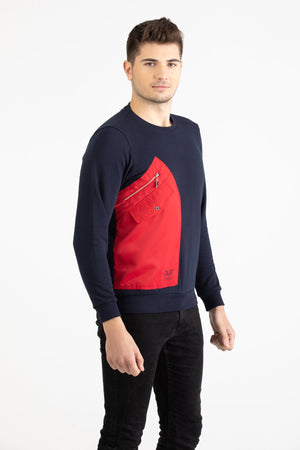 Man wearing a navy blue Versace 19.69 sweatshirt featuring a large red nylon utility pocket with zipper and snap details.